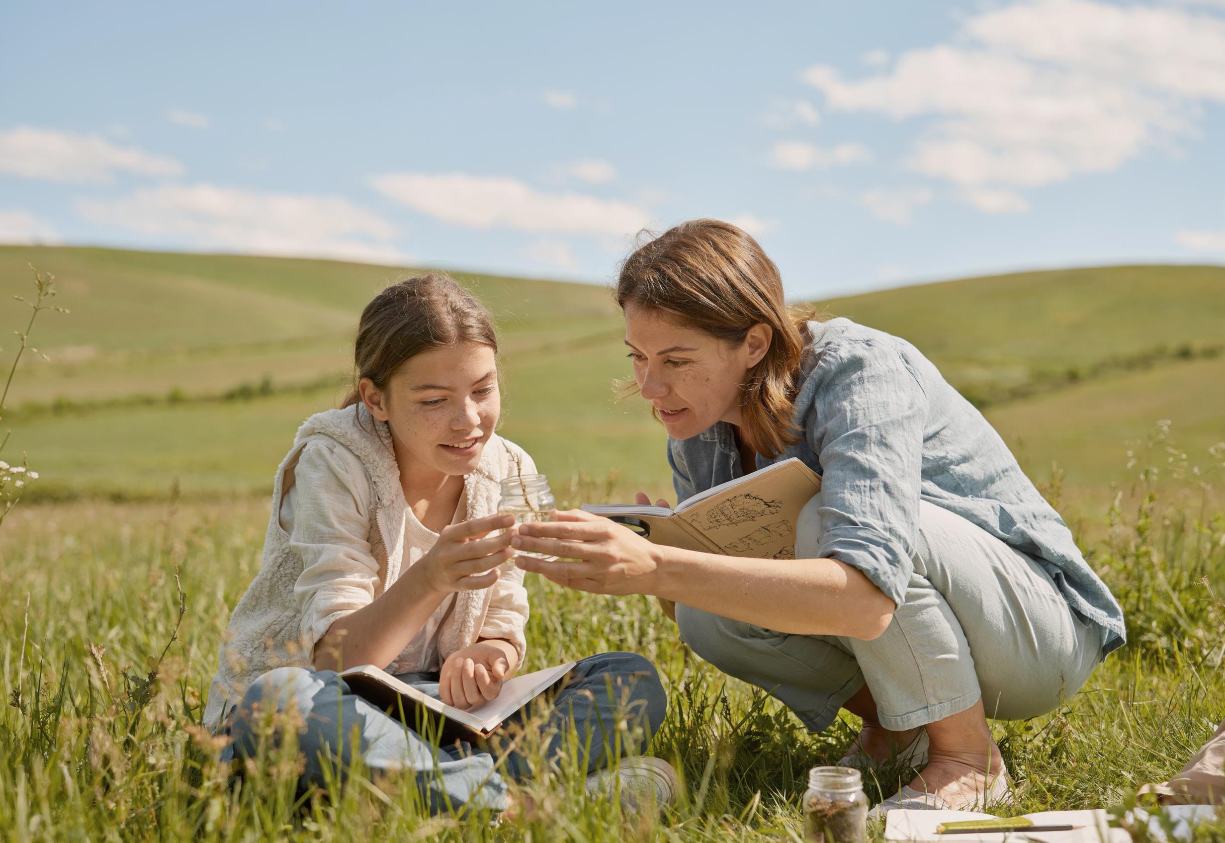 A teenage girl and her mother conducting a science experiment together in an open field